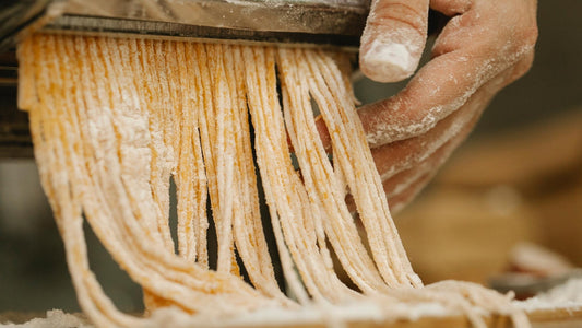 Hausgemachte italienische Pasta auf Holzbrett mit Mehl, Ei und Händen bei der Zubereitung – traditionelle Pasta wie in Italien